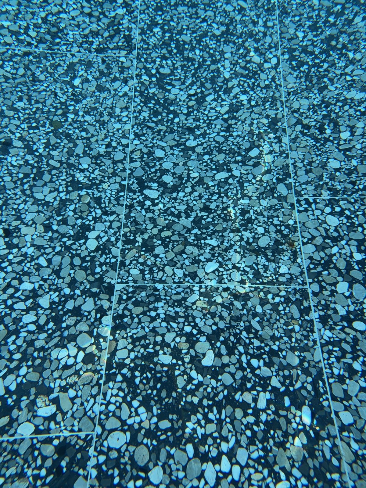 Kraakhelder zwembadwater boven een bodem in donkere terrazzo