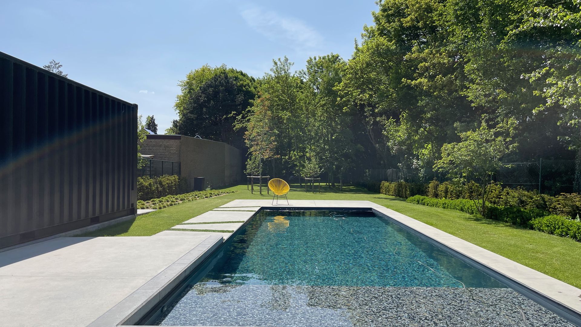 Rechthoekig privézwembad met helder water in een Belgische tuin, in vol daglicht