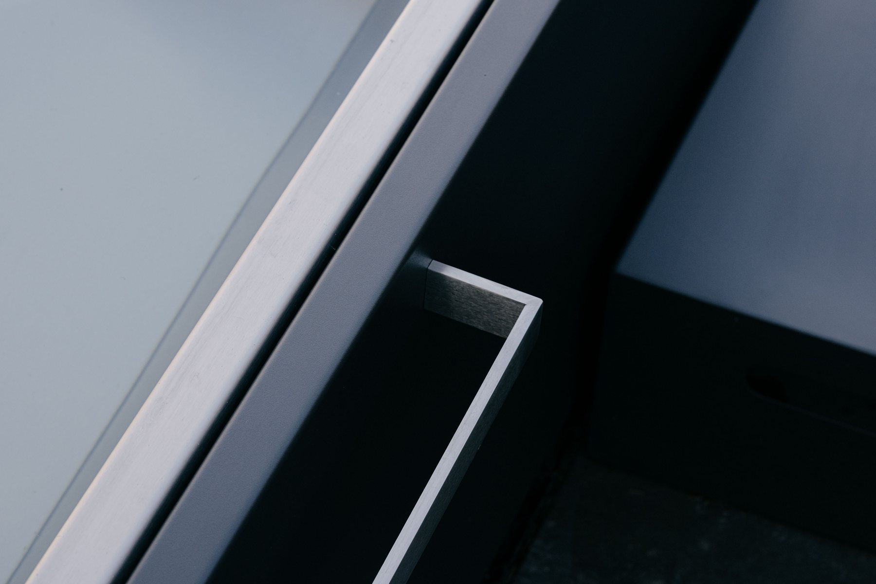Strak architecturaal detail van een inox zwembadrand in donker metaal