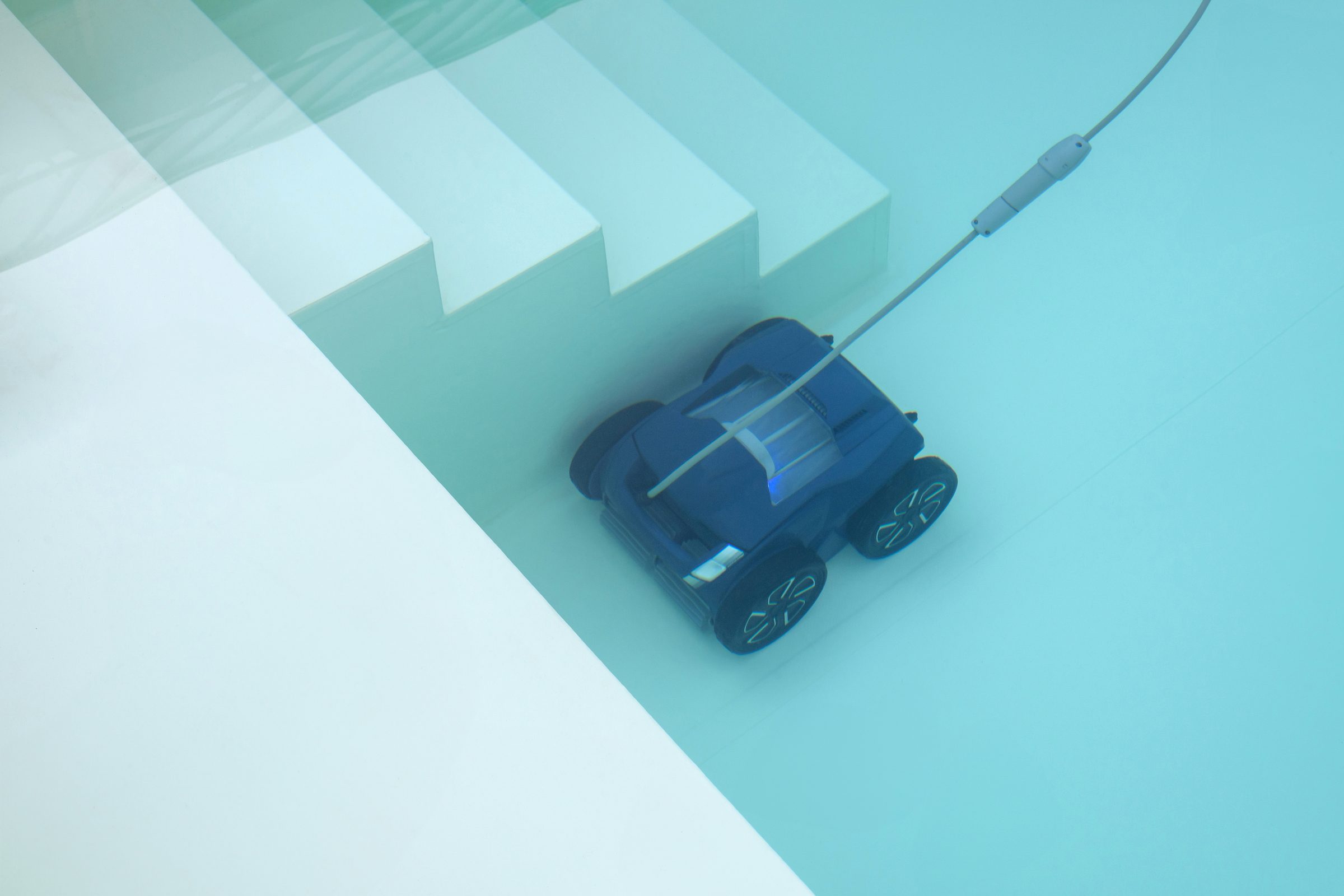Zwembadrobot aan het werk op de lichte bodem van een privébad, naast de trap