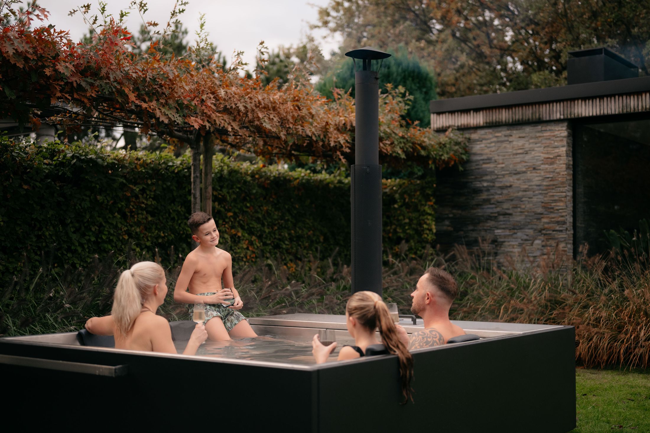 Gezin geniet samen in de dampende Silvertub in een herfsttuin